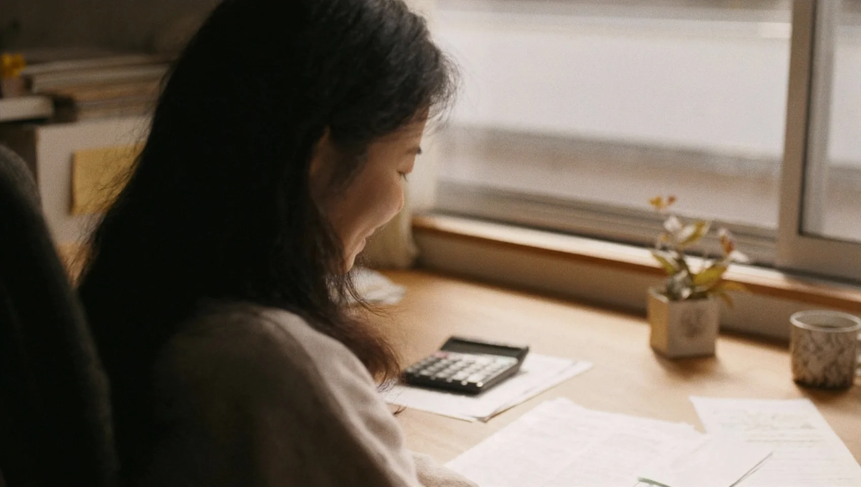 自宅の机で所得の見込みを計算しながらふるさと納税額を検討するイメージ